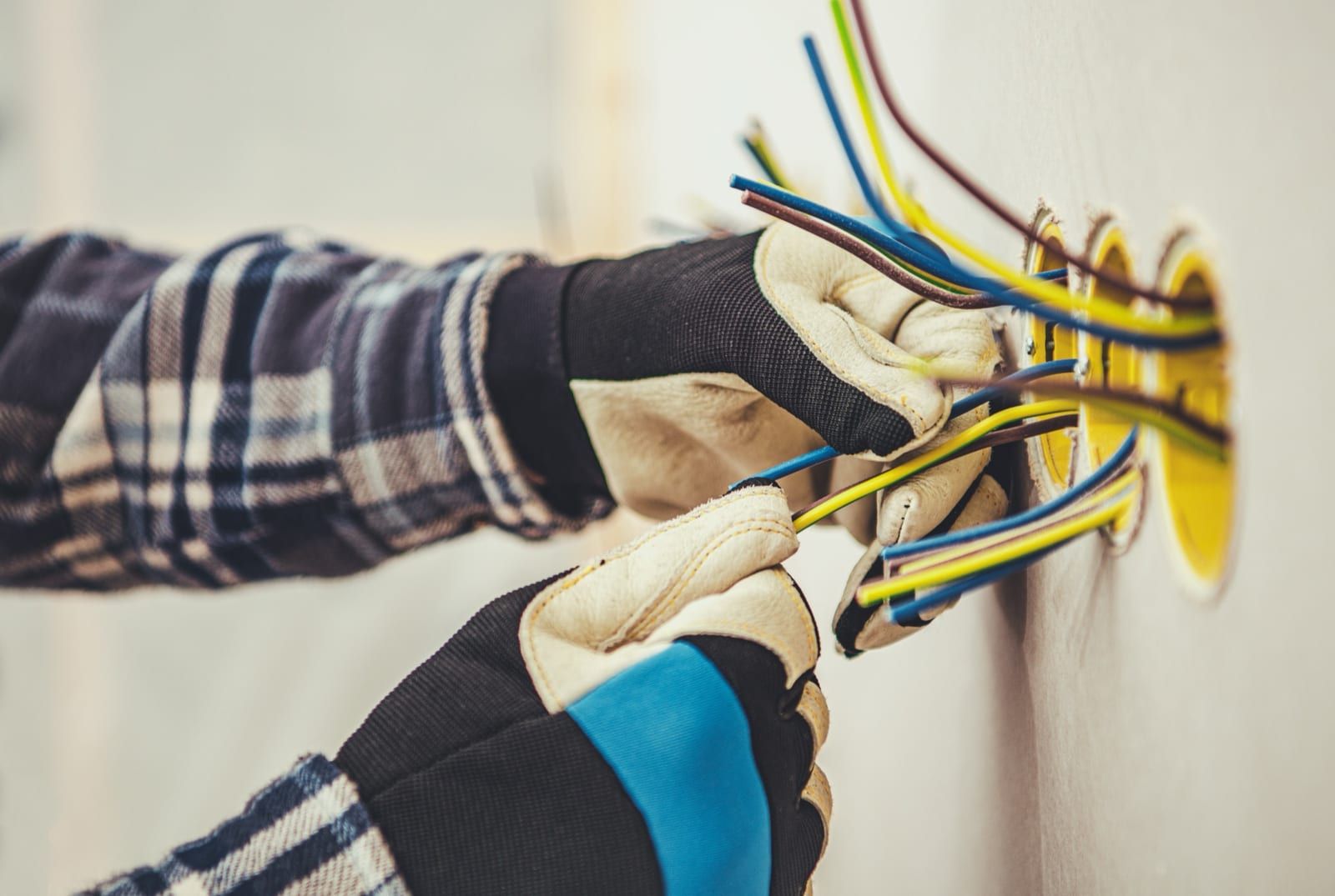 Técnico instalando cableado eléctrico con guantes de seguridad